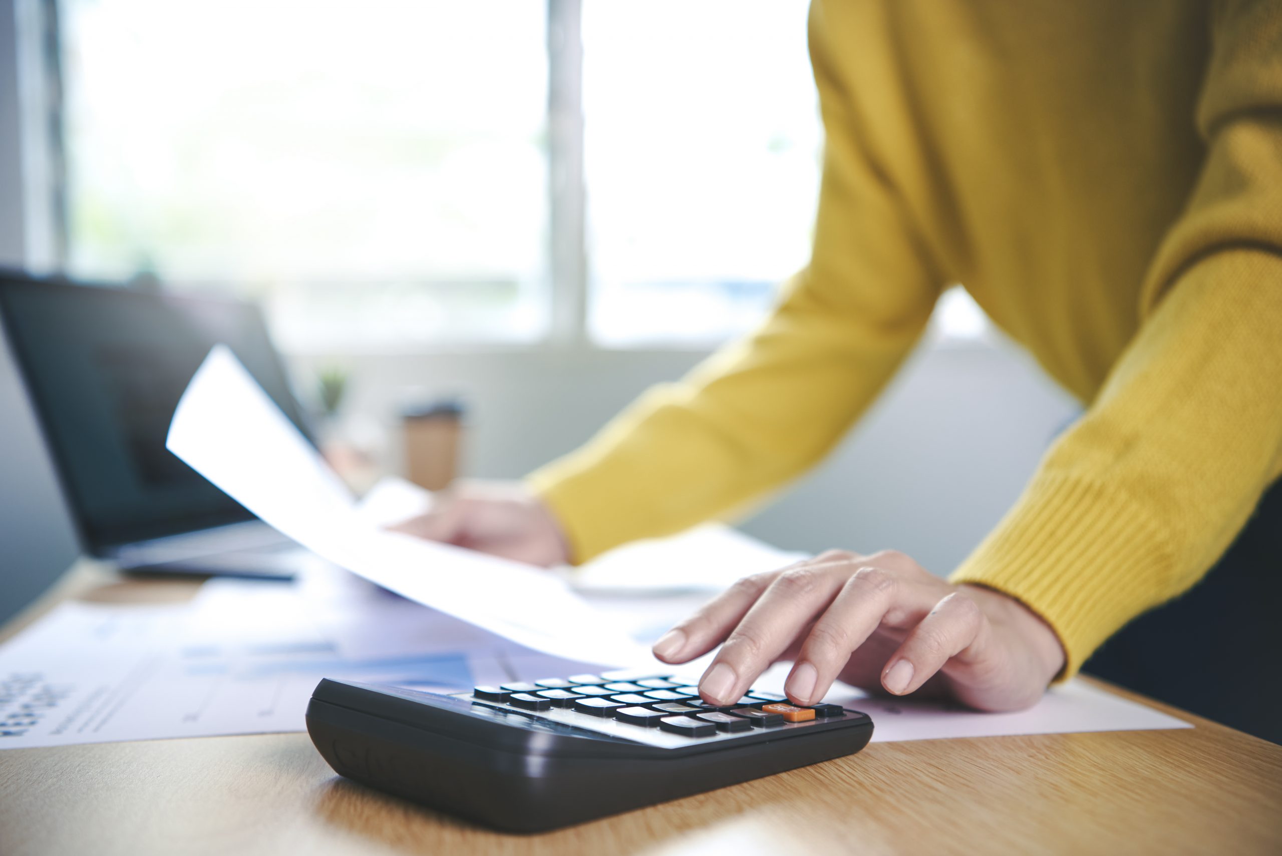 Business woman working in finance and accounting Analyze financial graph budget with calculator at home office.