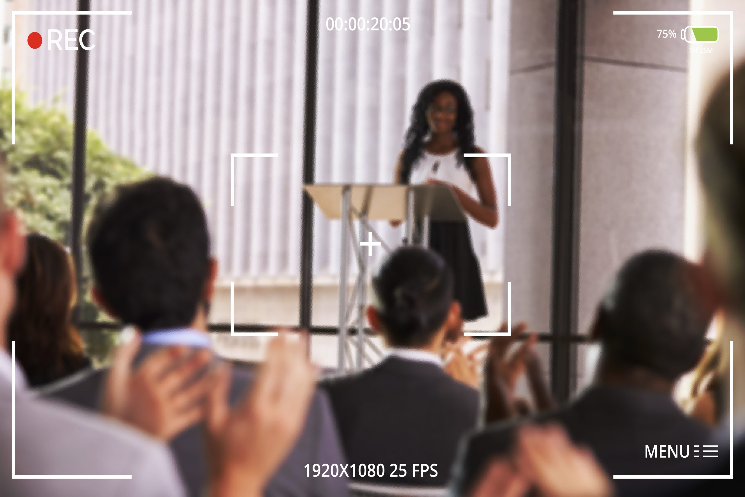 Audience at seminar applauding young black woman at lectern
