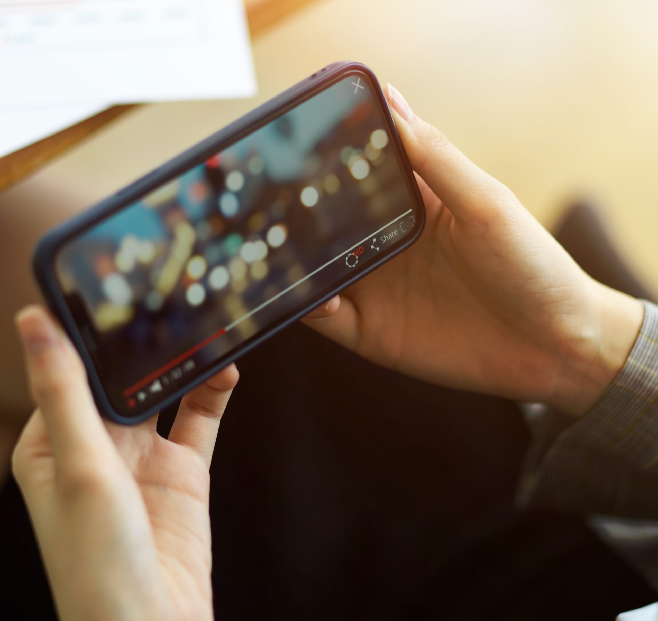Female is watching a video on her smart phone while holding it horizontally. bokeh video, enjoyment, relaxation