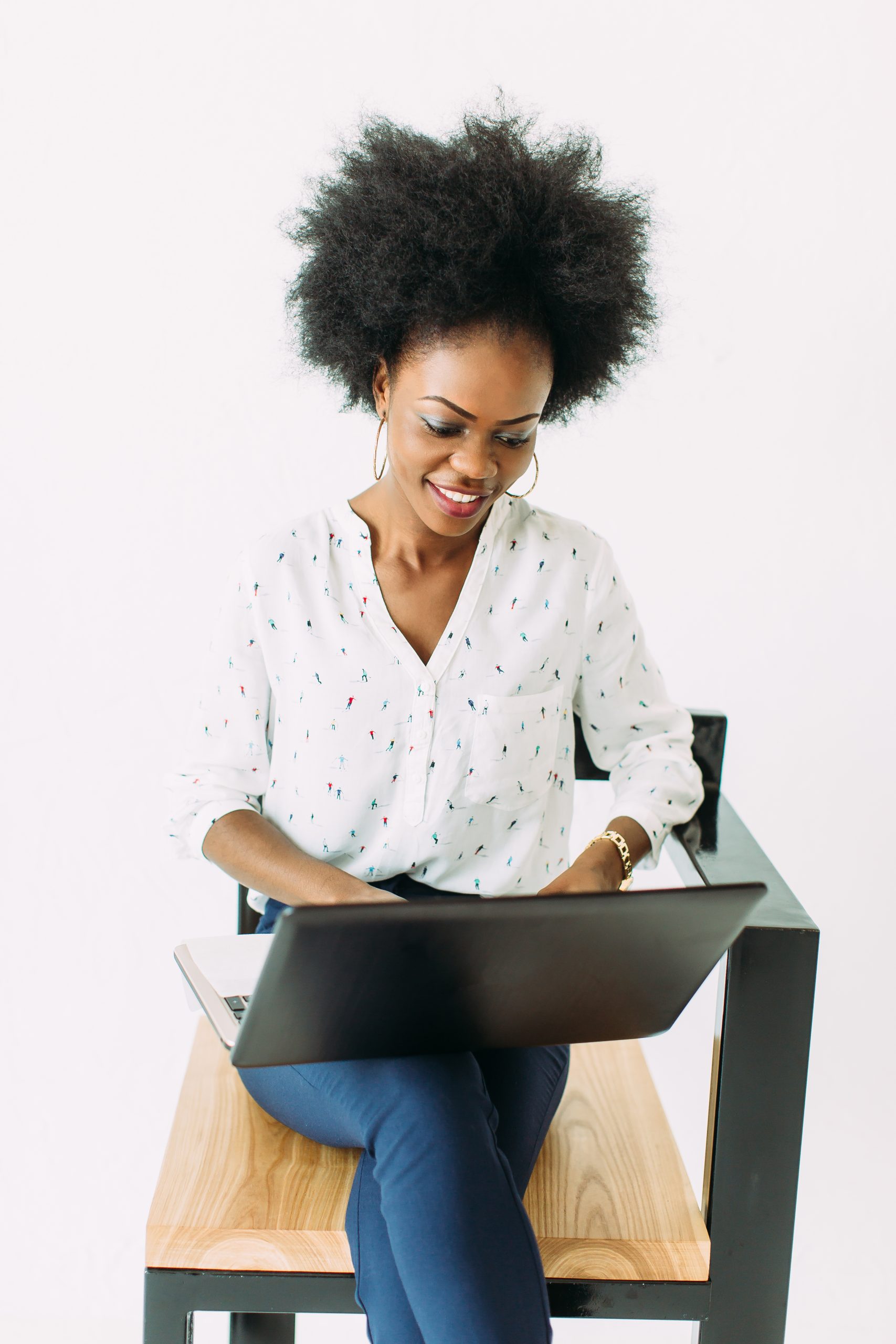 Young african american business woman typing on laptop while sitting on the chair, isolated on white.