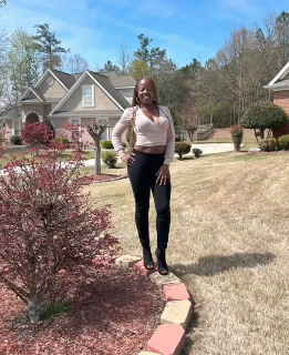 Black tax professional standing in front of large home.